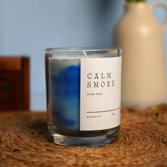 Candle labeled 'Calm Smoke' on a woven surface.