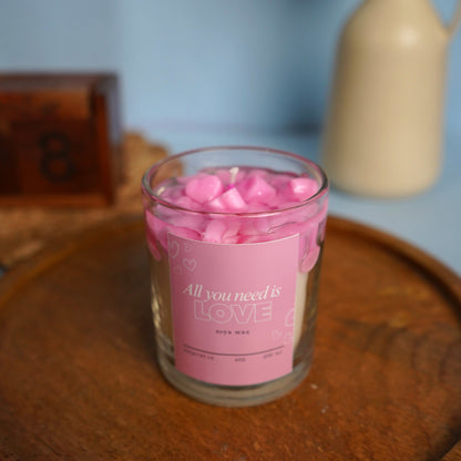 Candle jar with pink hearts on a wooden surface.